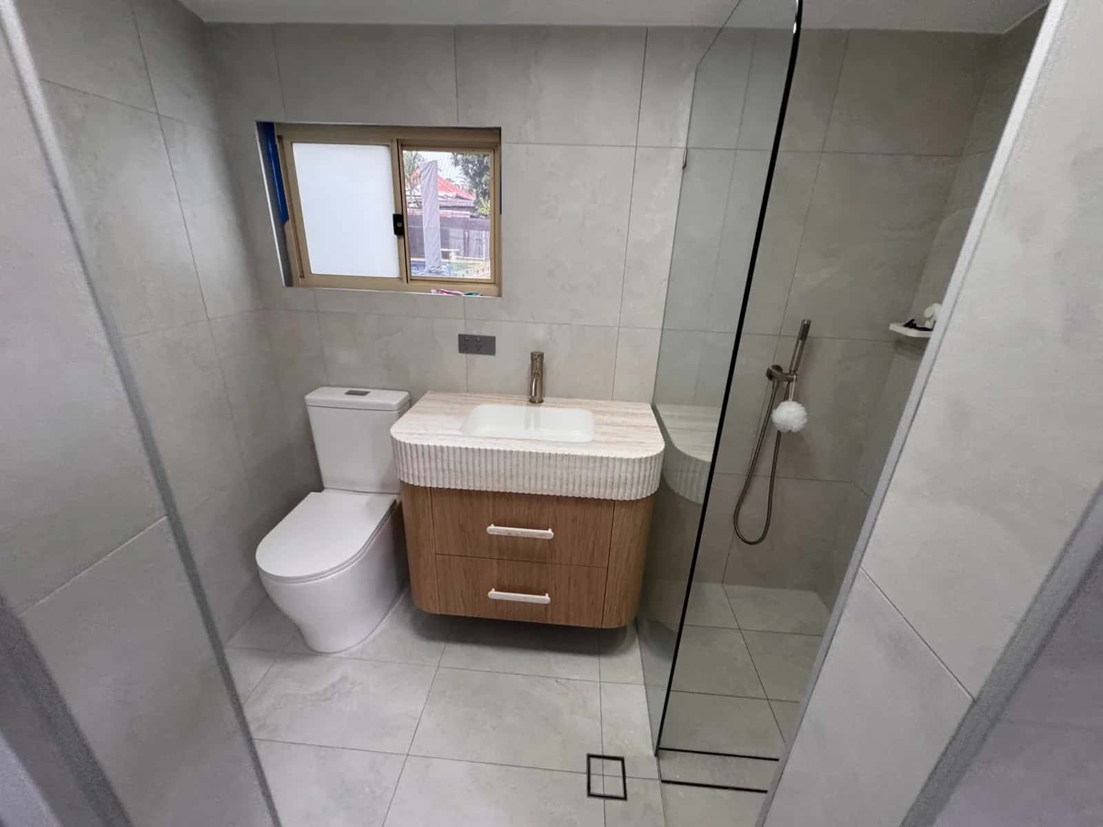 Completed Sydney bathroom renovation with a timber vanity, stone top, brushed brass tapware and a walk-in shower