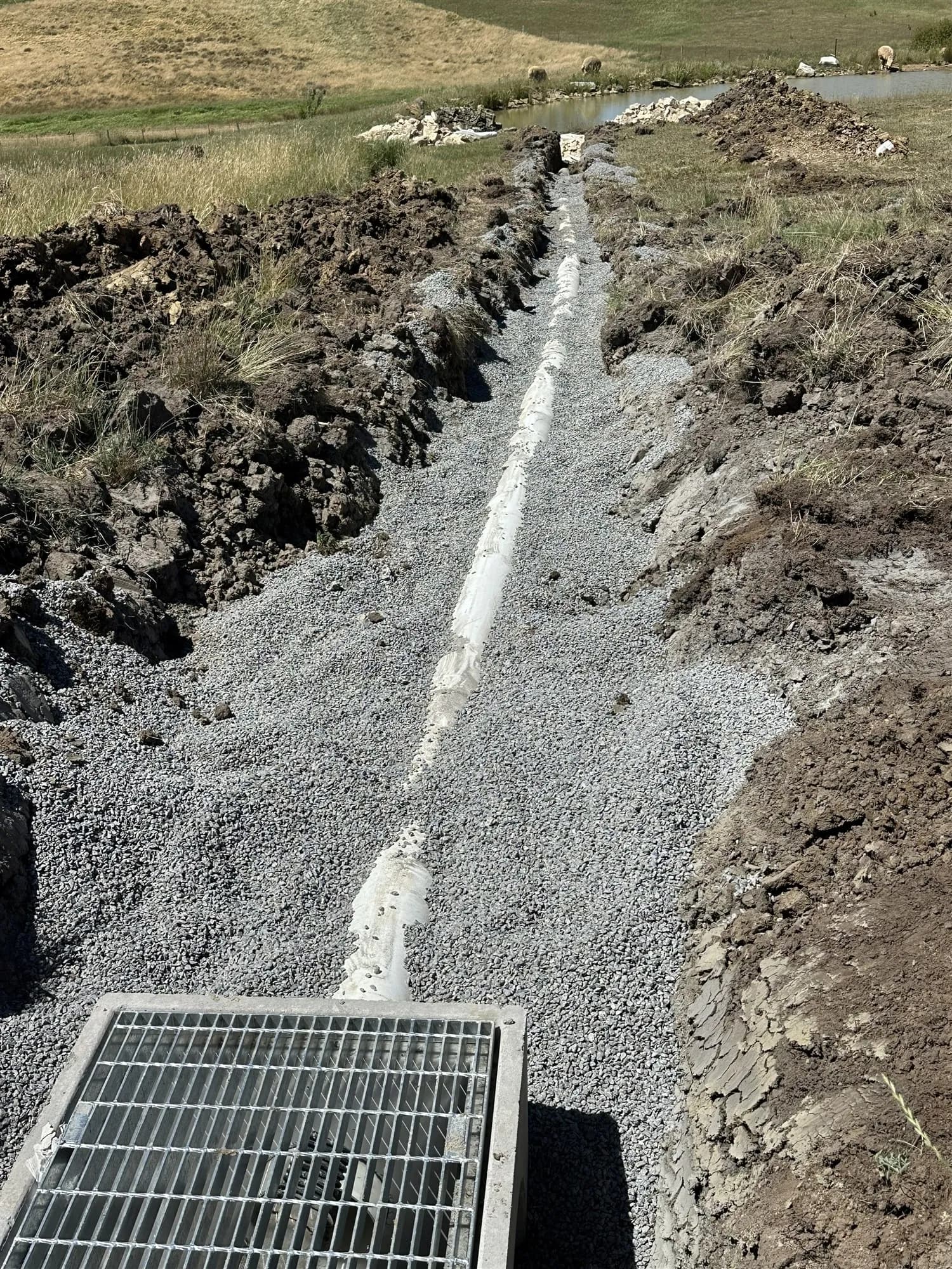 Grated stormwater pit at the end of a gravel-filled trench