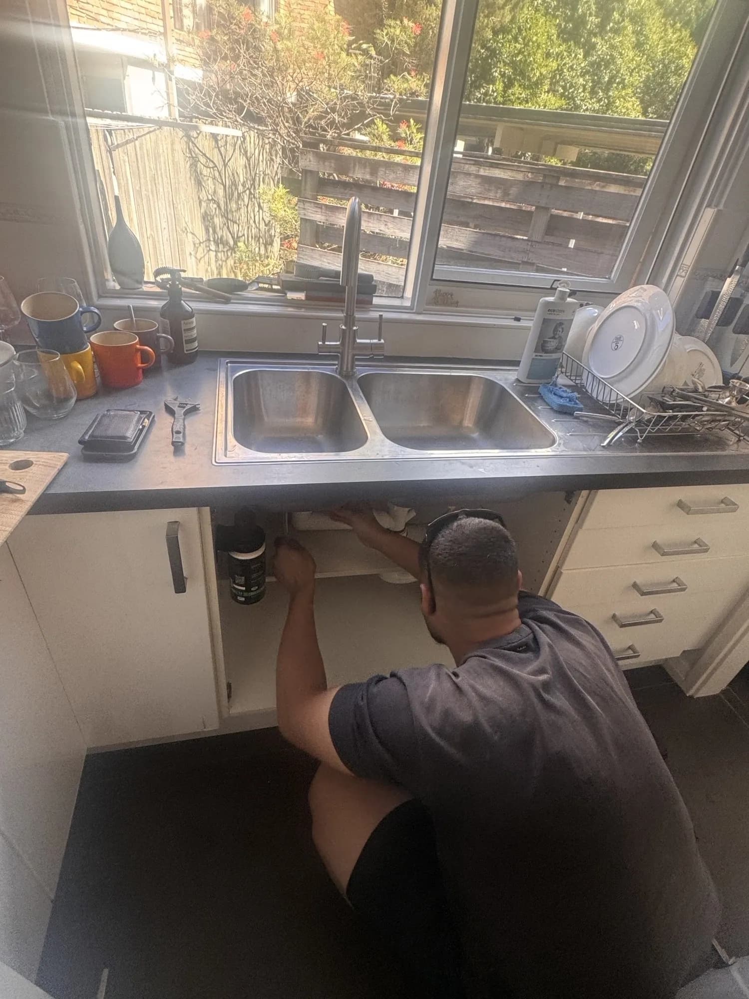 Plumber working in the cabinet under the Drummoyne kitchen sink to fit the Zip filtered mixer tap
