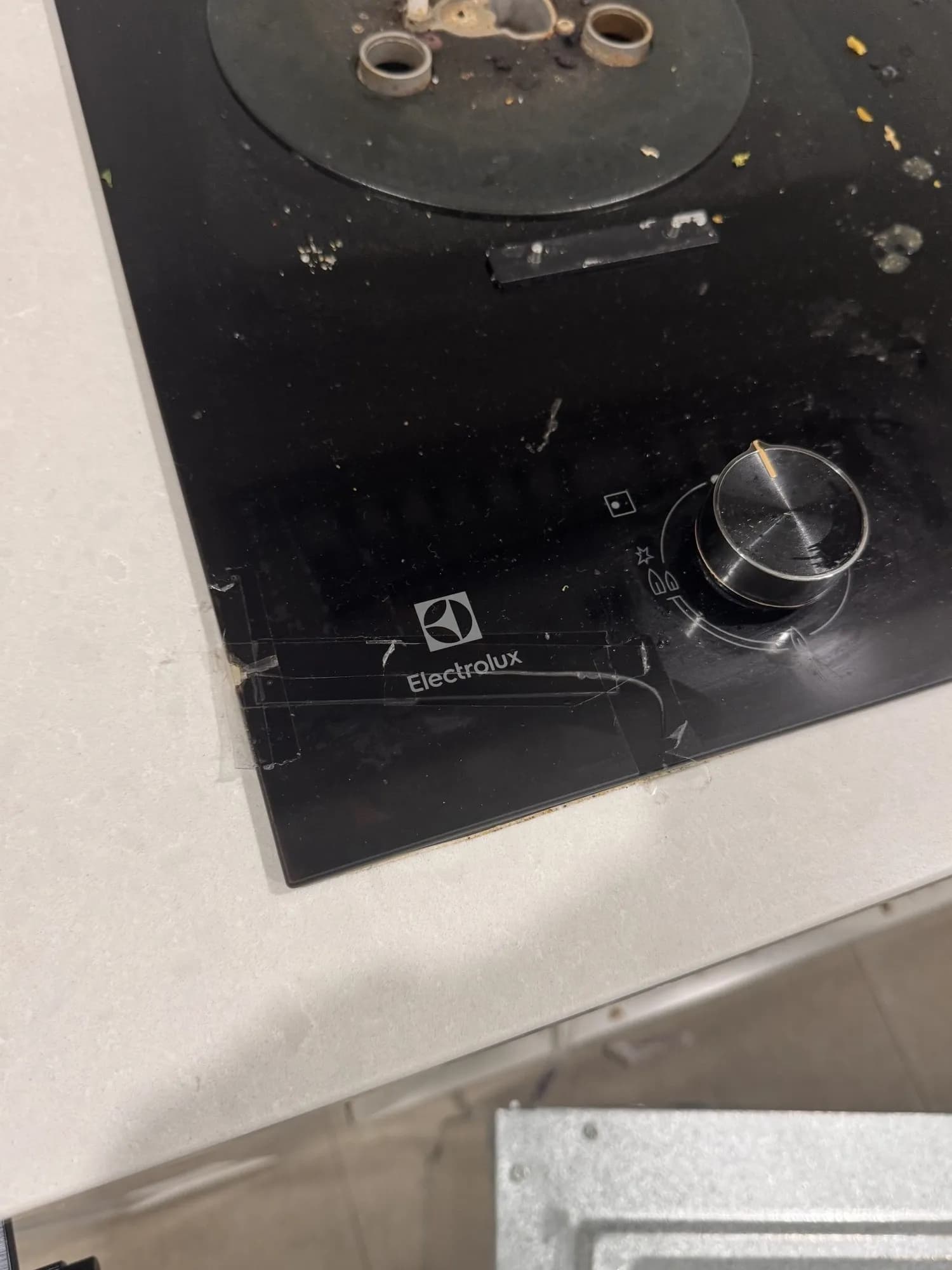 Close-up of the cracked glass on the old gas cooktop
