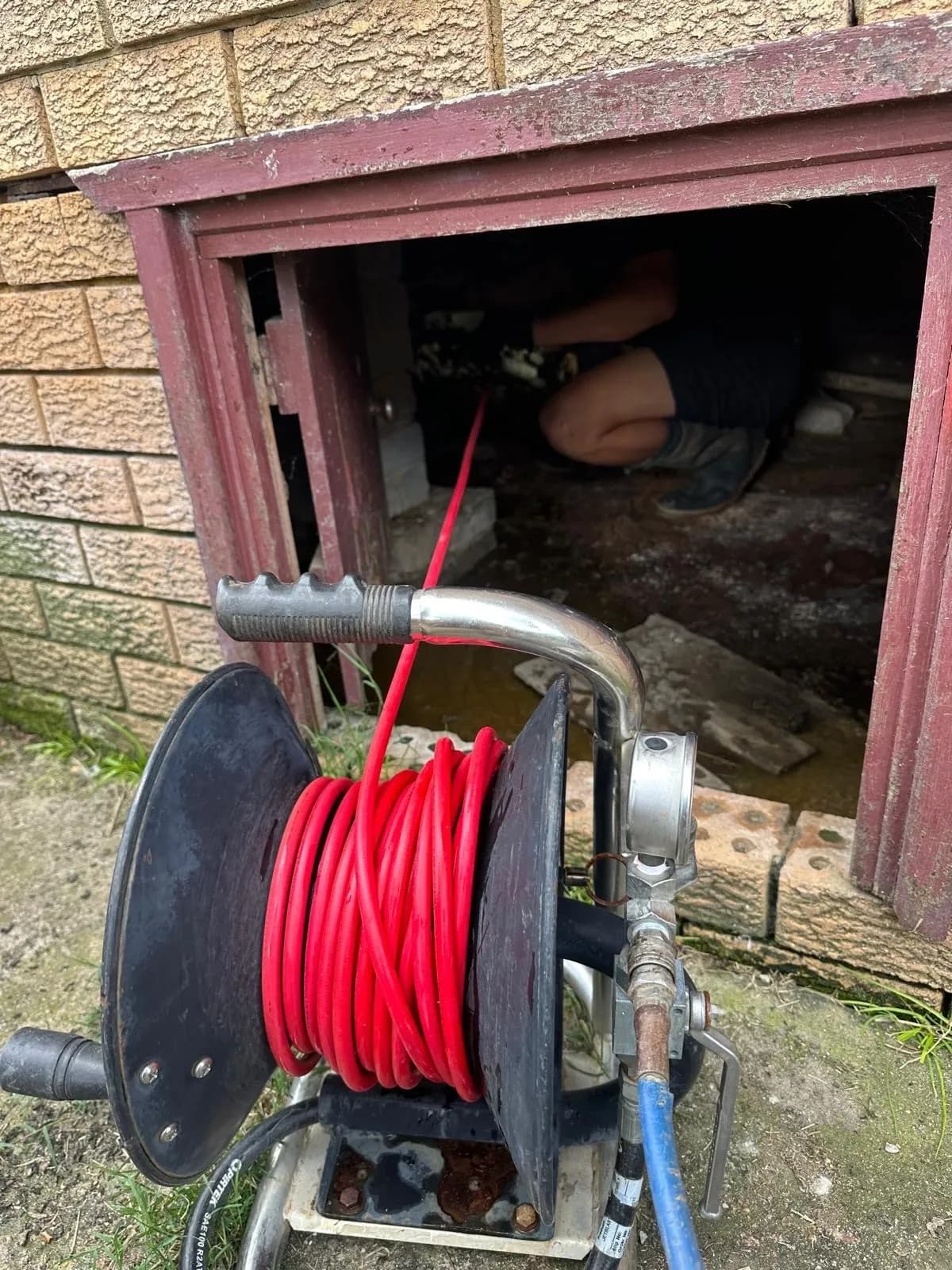 Jet blaster hose reel set up at the subfloor access of a house