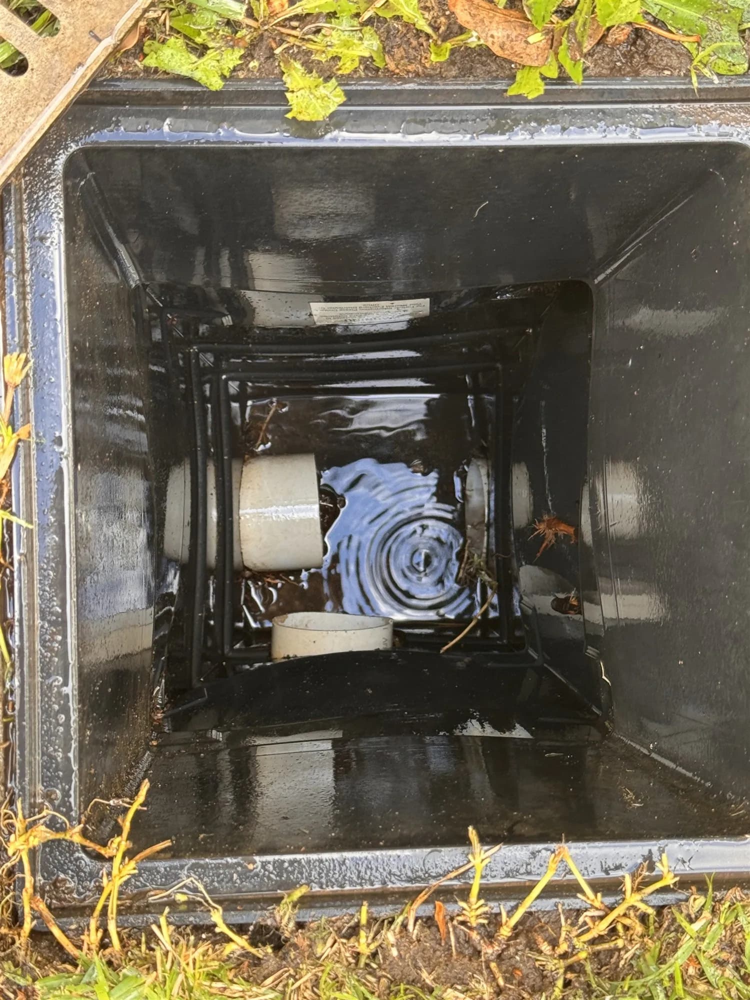 Cleared stormwater pit with water flowing through the pipe