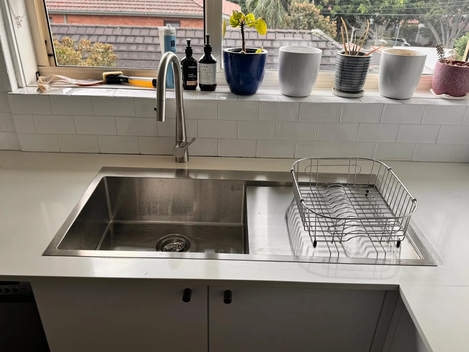 The same kitchen after installation, with a flush-mounted stainless sink and a pull-out mixer tap