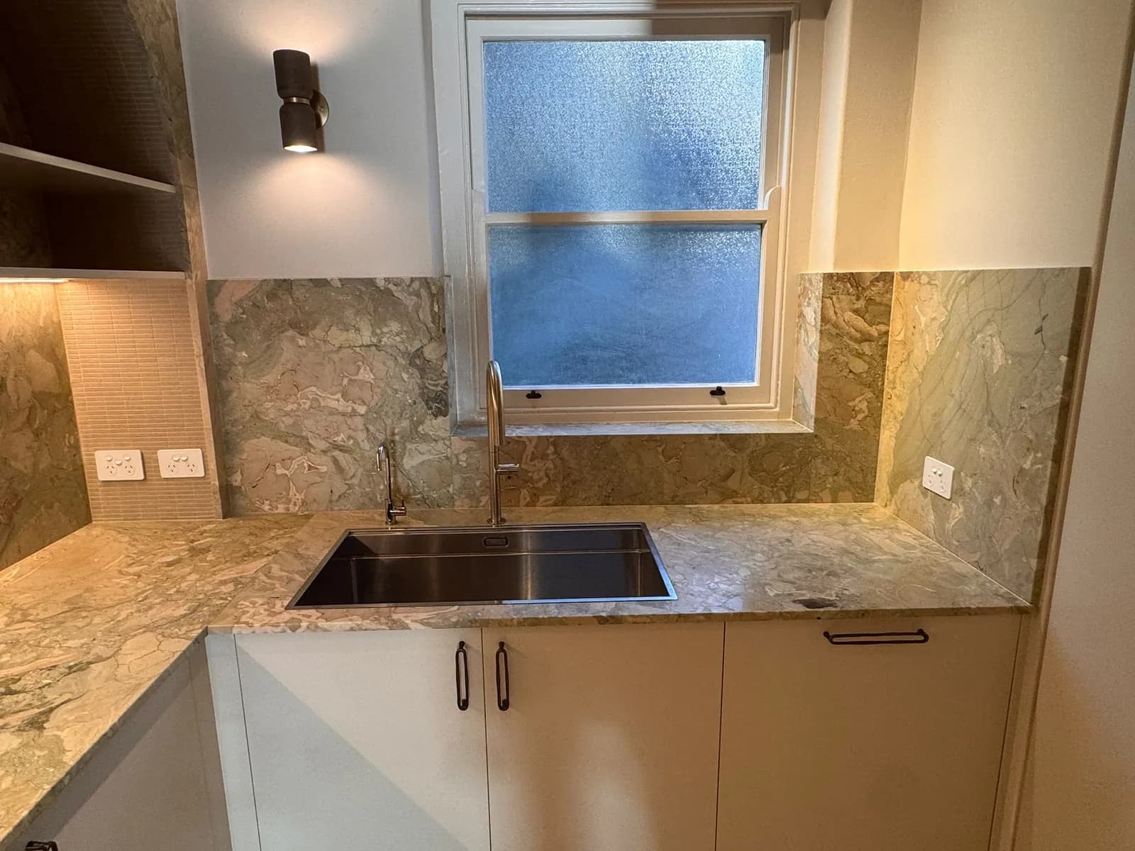 Completed Sydney kitchen with a stone benchtop and full slab splashback, undermount sink and gooseneck mixer tap