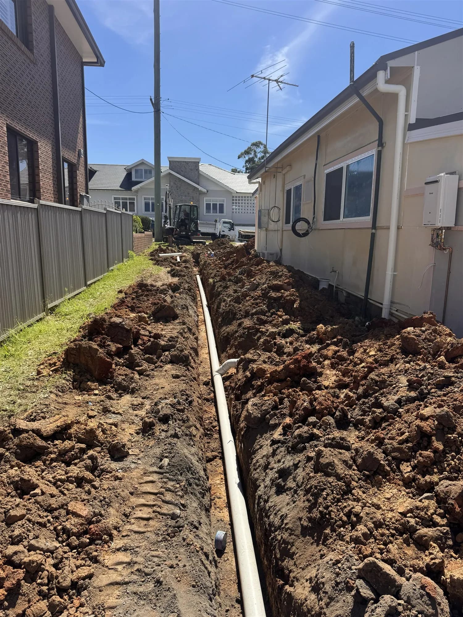 New 100 mm PVC stormwater line laid in a trench beside the house
