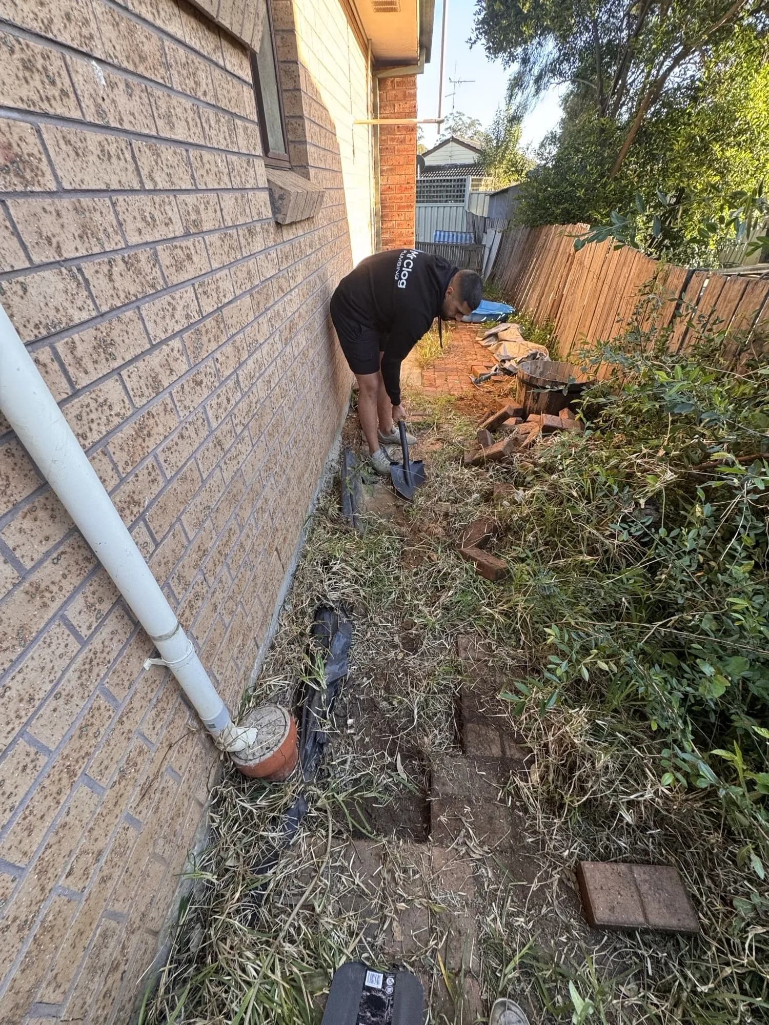 Digging down to the old clay sewer along the side of a brick house