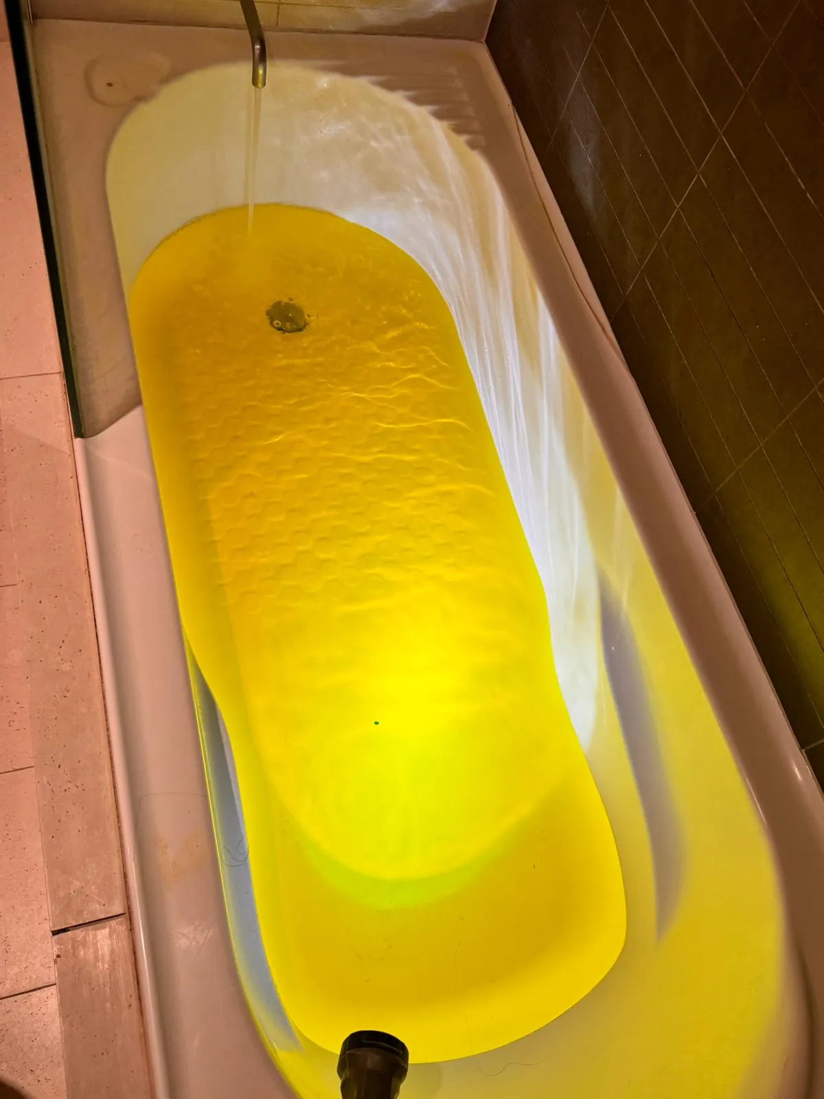 Bath filled with bright fluorescent yellow dyed water during a leak detection dye test